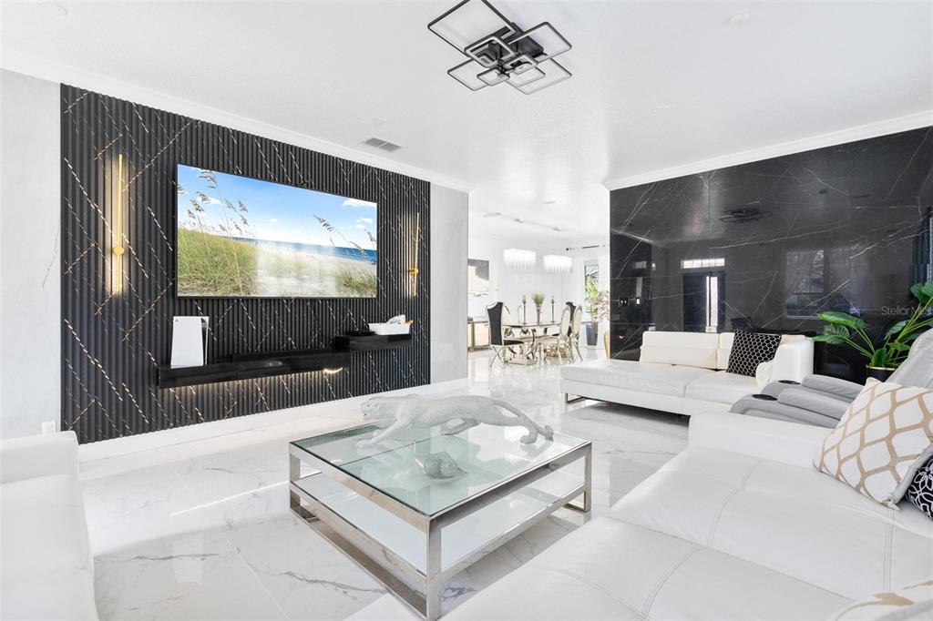 A modern living room features a black slatted accent wall, white leather sofas, and marble flooring — 400 BROOKFIELD TERRACE, DELAND, FL