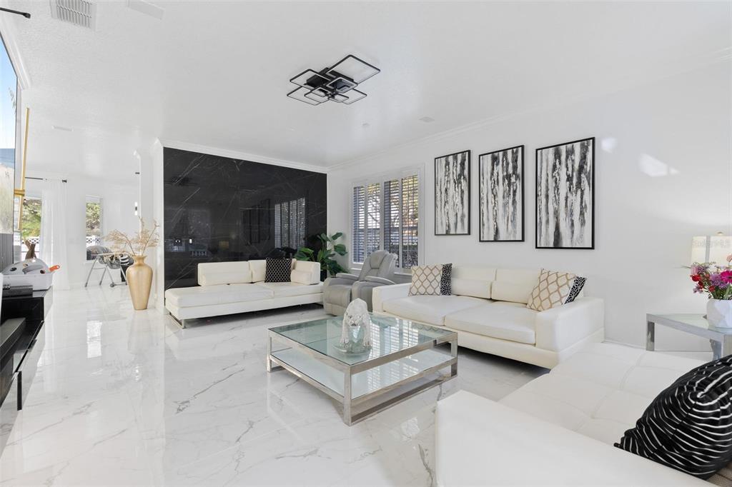 A modern living room features white leather sofas, a glass coffee table, and black marble wall — 400 BROOKFIELD TERRACE, DELAND, FL