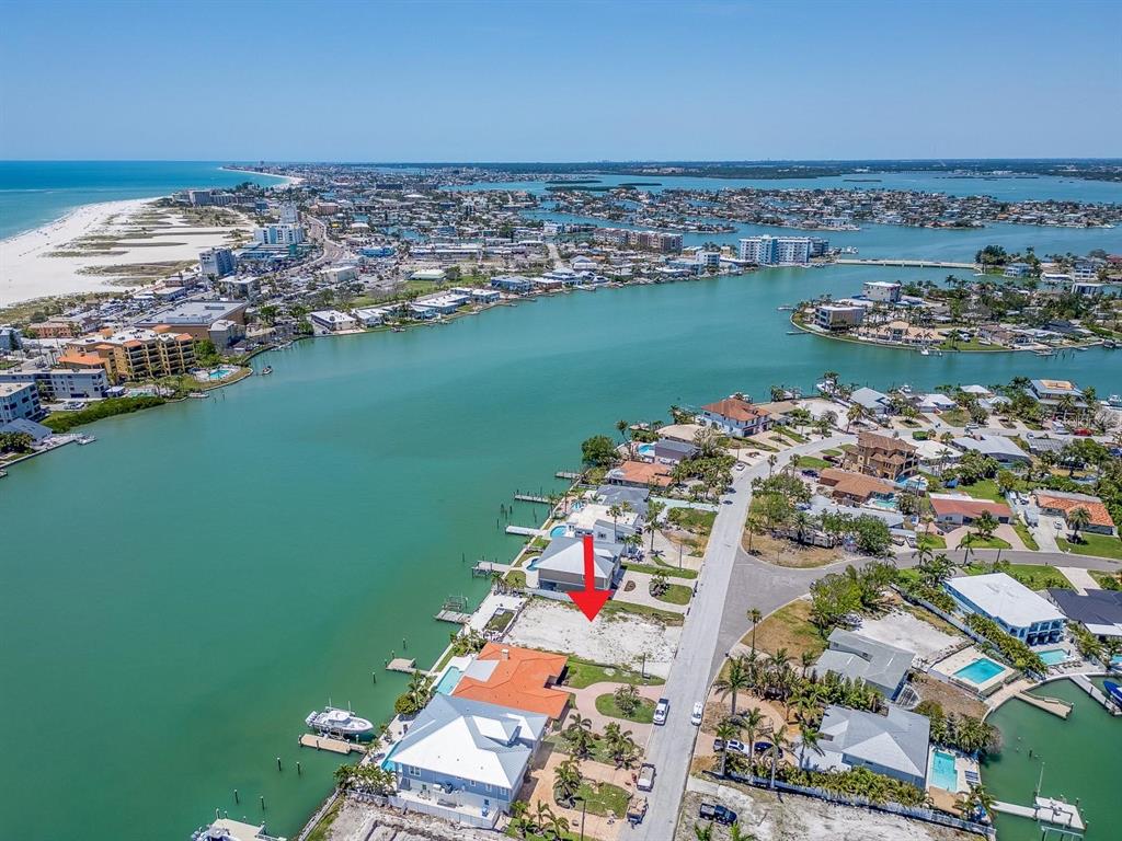 An aerial view shows a vacant waterfront lot marked with a red arrow — 10126 TARPON DRIVE, TREASURE ISLAND, FL