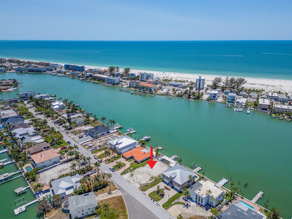 An aerial view shows a vacant waterfront lot situated between two houses along a canal — 10126 TARPON DRIVE, TREASURE ISLAND, FL