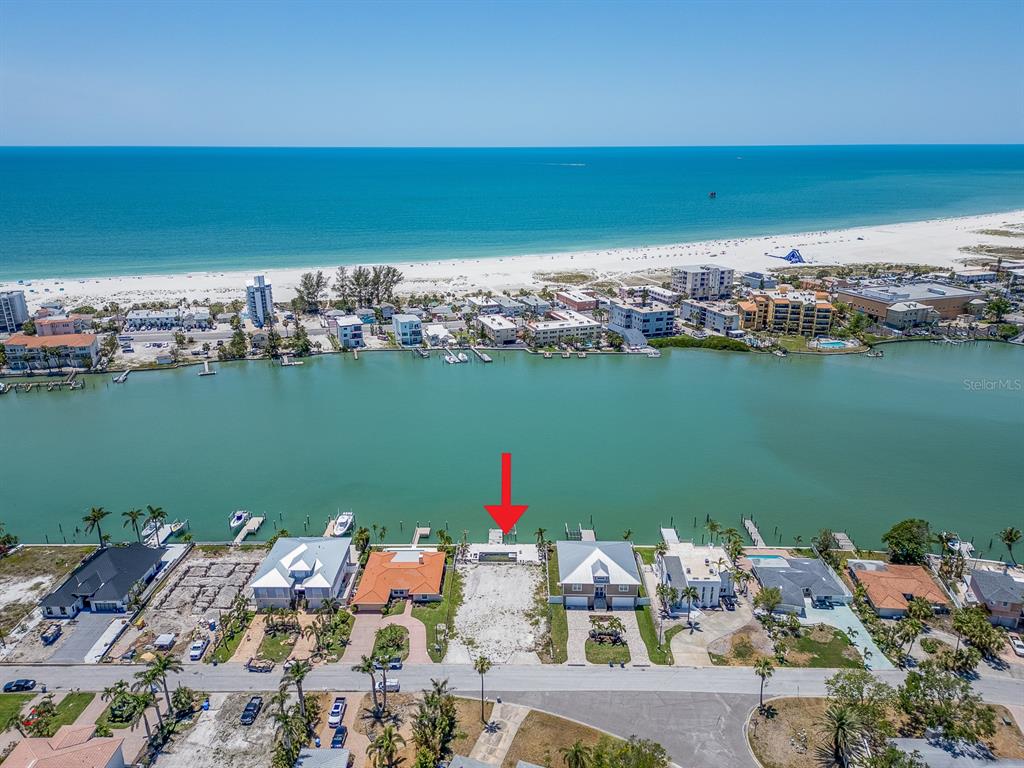 An aerial view shows a vacant waterfront lot with a dock between two houses — 10126 TARPON DRIVE, TREASURE ISLAND, FL