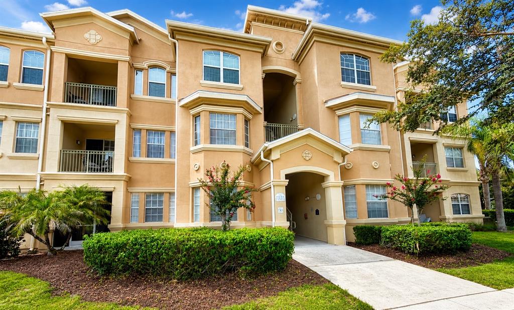 A multi-story tan stucco apartment building features balconies, bay windows, and a central entryway — 313 TERRACE RIDGE CIRCLE UNIT 313, DAVENPORT, FL