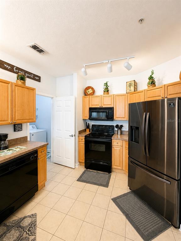 A kitchen features light wood cabinets, black appliances, and tile flooring — 313 TERRACE RIDGE CIRCLE UNIT 313, DAVENPORT, FL