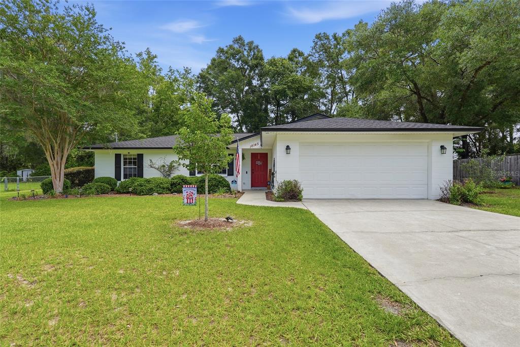 A single-story white house with a red front door and a two-car garage — 18145 NW 250TH TERRACE, HIGH SPRINGS, FL