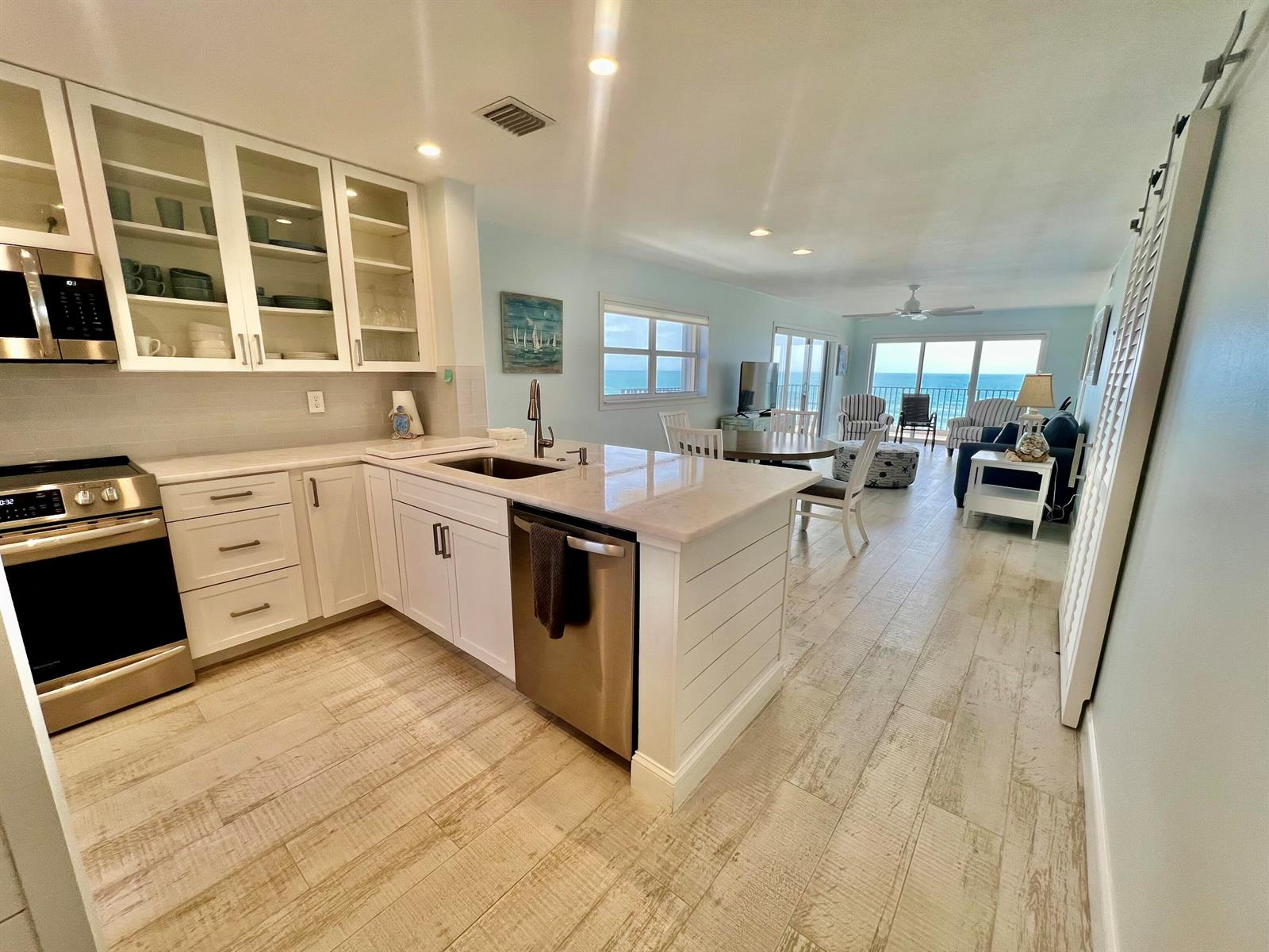 A white kitchen with stainless steel appliances opens into a living area with ocean views — 7410 S Ocean Drive # 505, Jensen Beach FL 34957, JENSEN BEACH, FL