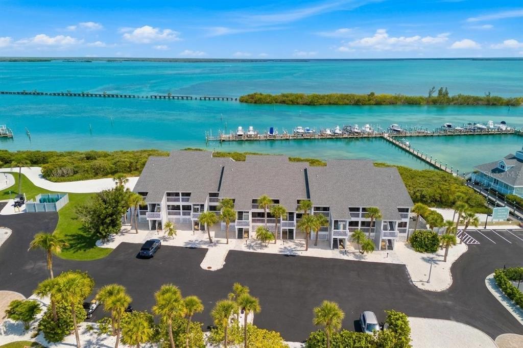 An aerial view shows a multi-story apartment building with a parking lot and boat docks — 6030 BOCA GRANDE CAUSEWAY UNIT B21, BOCA GRANDE, FL
