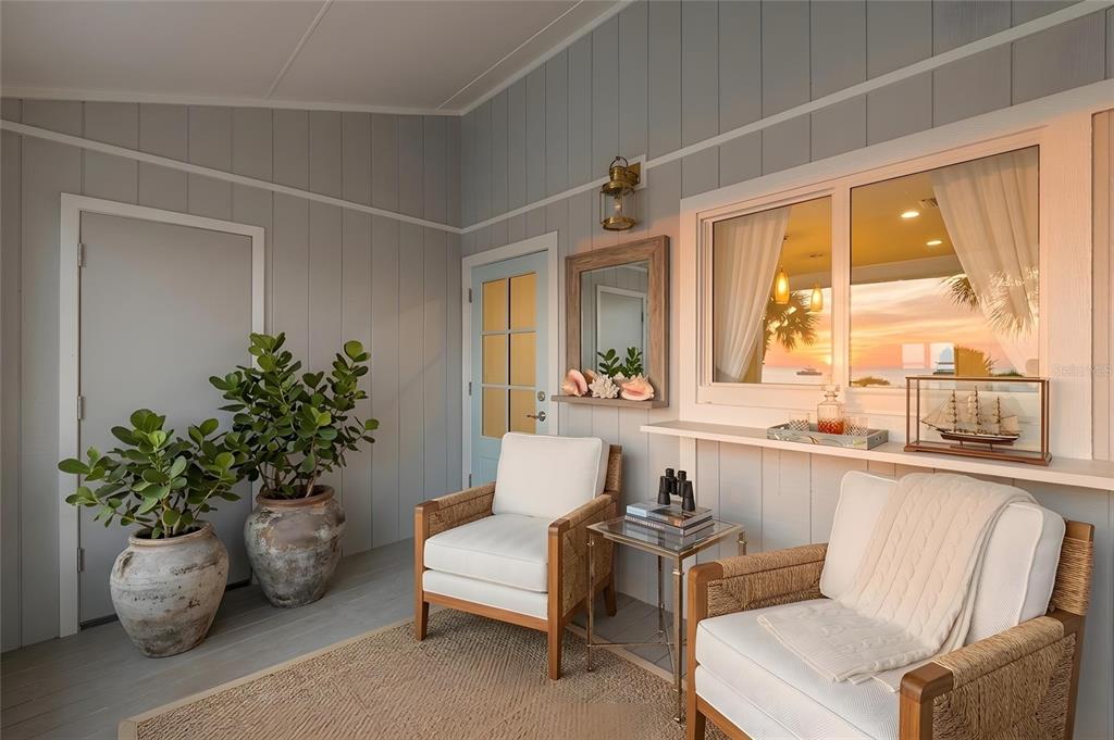 A sunroom features two white armchairs, potted plants, and a window overlooking a sunset view — 6030 BOCA GRANDE CAUSEWAY UNIT B21, BOCA GRANDE, FL