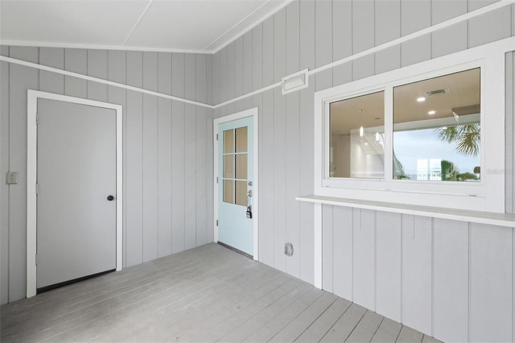 A covered porch with gray vertical siding, a light blue door, and a serving window — 6030 BOCA GRANDE CAUSEWAY UNIT B21, BOCA GRANDE, FL