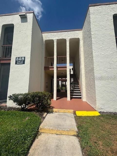 An exterior view of a multi-story apartment building with a central staircase and walkway — 528 ORANGE DRIVE UNIT 26, ALTAMONTE SPRINGS, FL