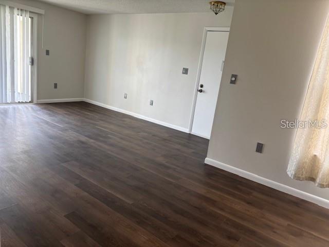 An empty living room features dark wood-look flooring, light-colored walls, and a sliding glass door — 528 ORANGE DRIVE UNIT 26, ALTAMONTE SPRINGS, FL