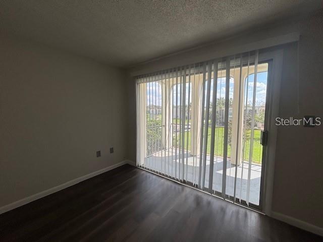An empty room with dark wood-look flooring and vertical blinds covering a sliding glass door — 528 ORANGE DRIVE UNIT 26, ALTAMONTE SPRINGS, FL