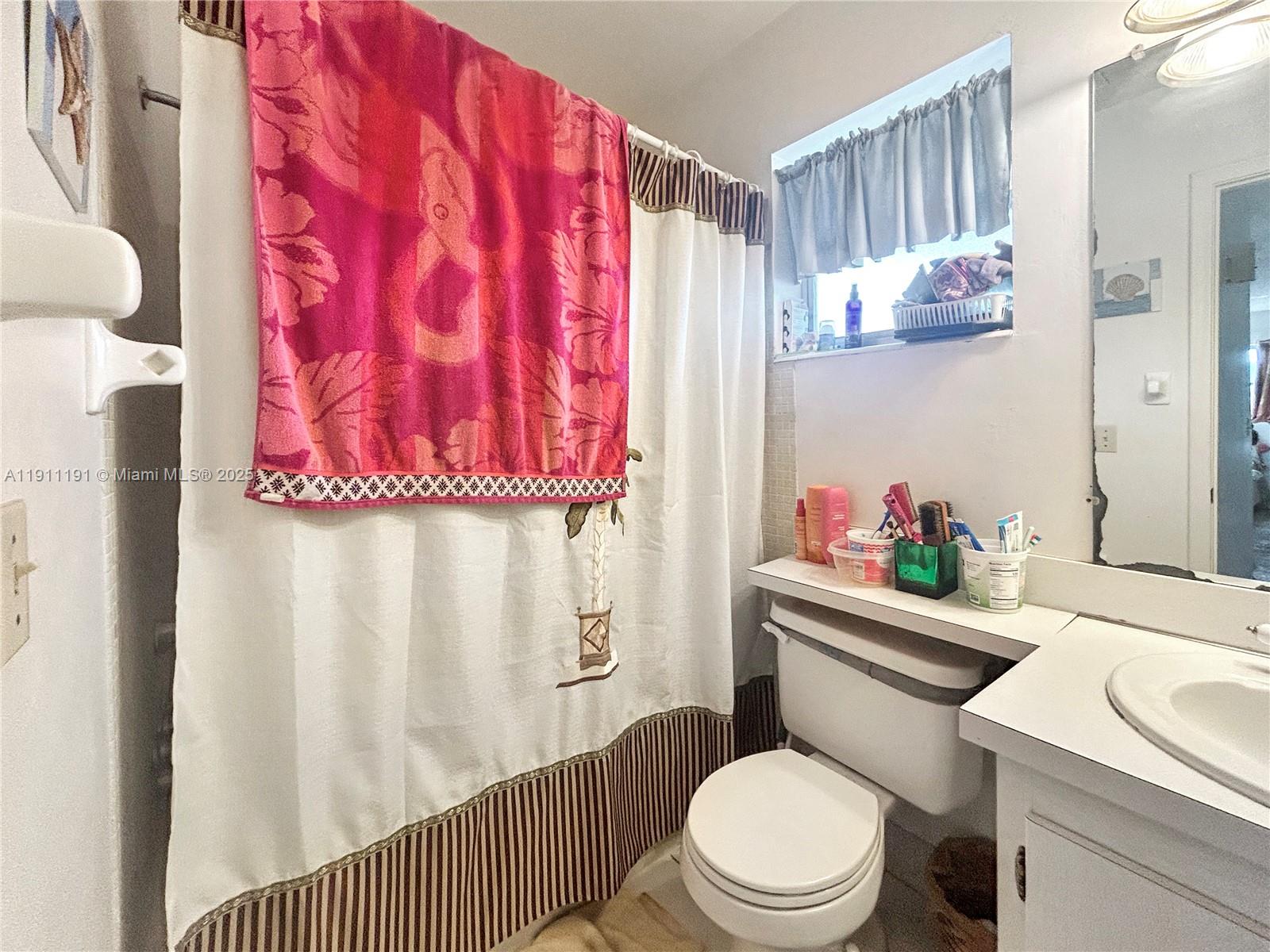 A bathroom features a shower curtain, a toilet, a vanity, and a window with curtains — 2112 NE 1st Way # 203, Boynton Beach FL 33435, BOYNTON BEACH, FL