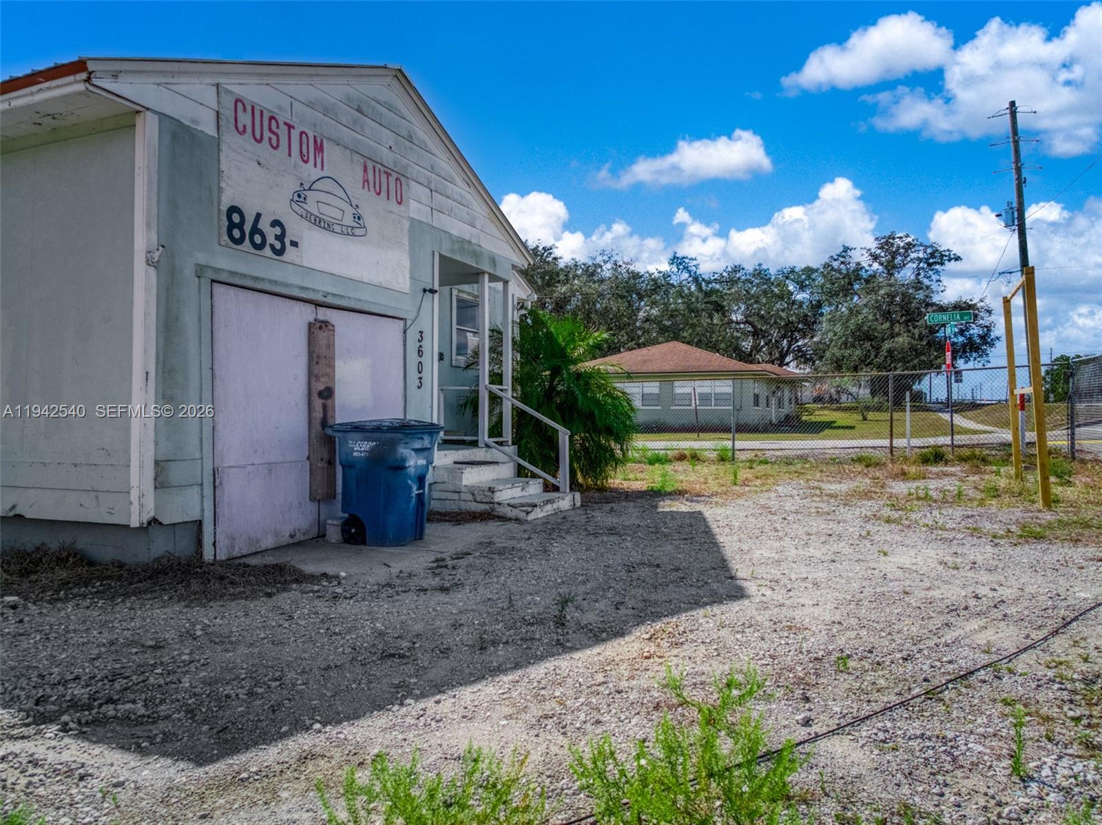 A weathered, light-colored commercial building with a garage door sits on a gravel lot — 3603 Kenilworth Blvd, Sebring FL 33870, SEBRING, FL