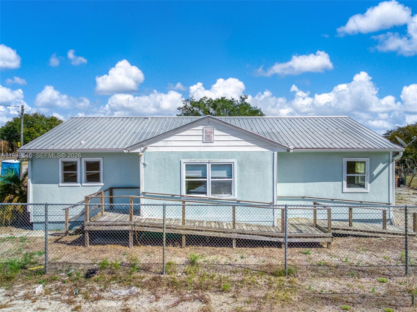A light blue, single-story house features a metal roof and a wooden wheelchair ramp — 3603 Kenilworth Blvd, Sebring FL 33870, SEBRING, FL