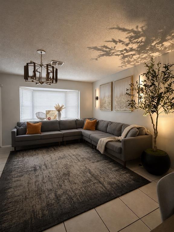 A living room features a gray sectional sofa, a large area rug, and a potted tree — 10344 COUNCILS WAY, TAMPA, FL