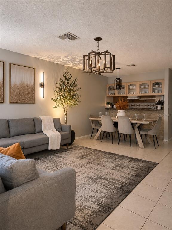 A living and dining area features a gray sofa, area rug, and a geometric chandelier — 10344 COUNCILS WAY, TAMPA, FL
