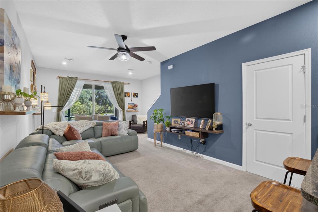 A living room features a grey sectional sofa, a blue accent wall, and a television — 2911 JACOB CROSSING LANE, HOLIDAY, FL