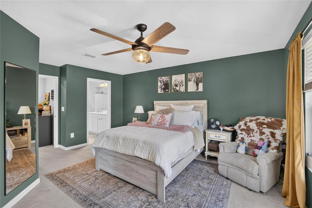 A bedroom features dark green walls, a light wood bed frame, and a ceiling fan — 2911 JACOB CROSSING LANE, HOLIDAY, FL