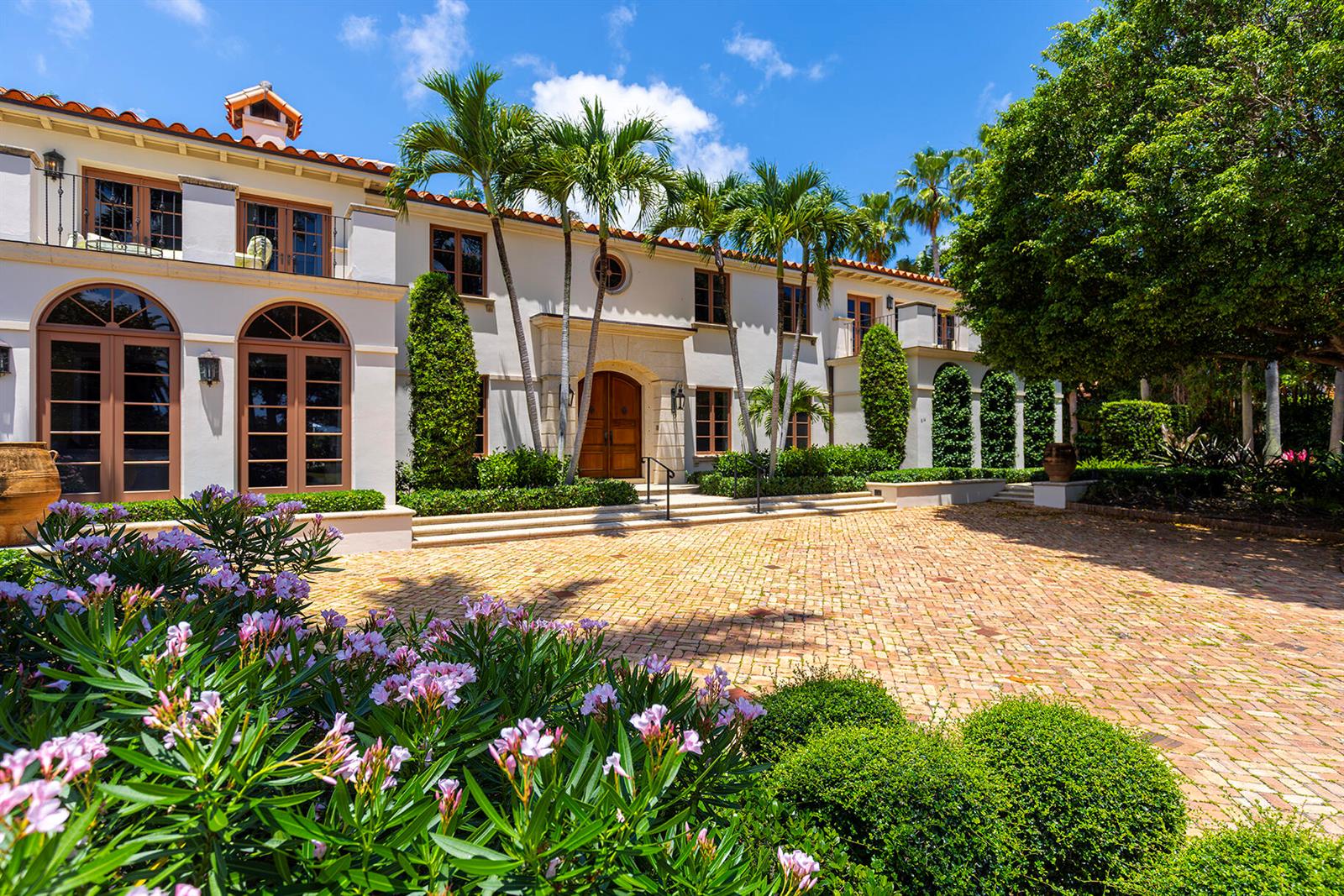 A two-story Mediterranean-style home features a brick courtyard, palm trees, and arched glass doors — 614 Tarpon Way, Palm Beach FL 33480, PALM BEACH, FL