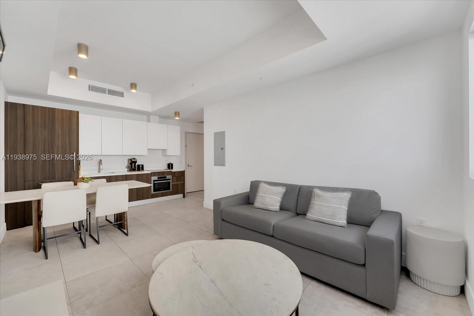 A modern open-concept living area features a kitchen with wood cabinetry and a gray sofa — 239 SW 9th St # 1603, Miami FL 33130, MIAMI, FL