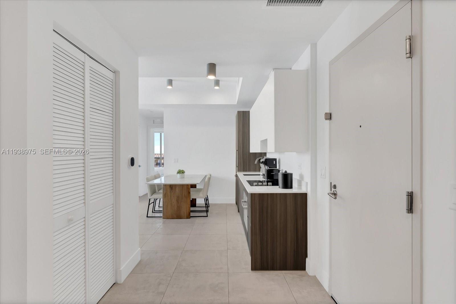 A modern kitchen with dark wood cabinets and white countertops opens into a dining area — 239 SW 9th St # 1603, Miami FL 33130, MIAMI, FL