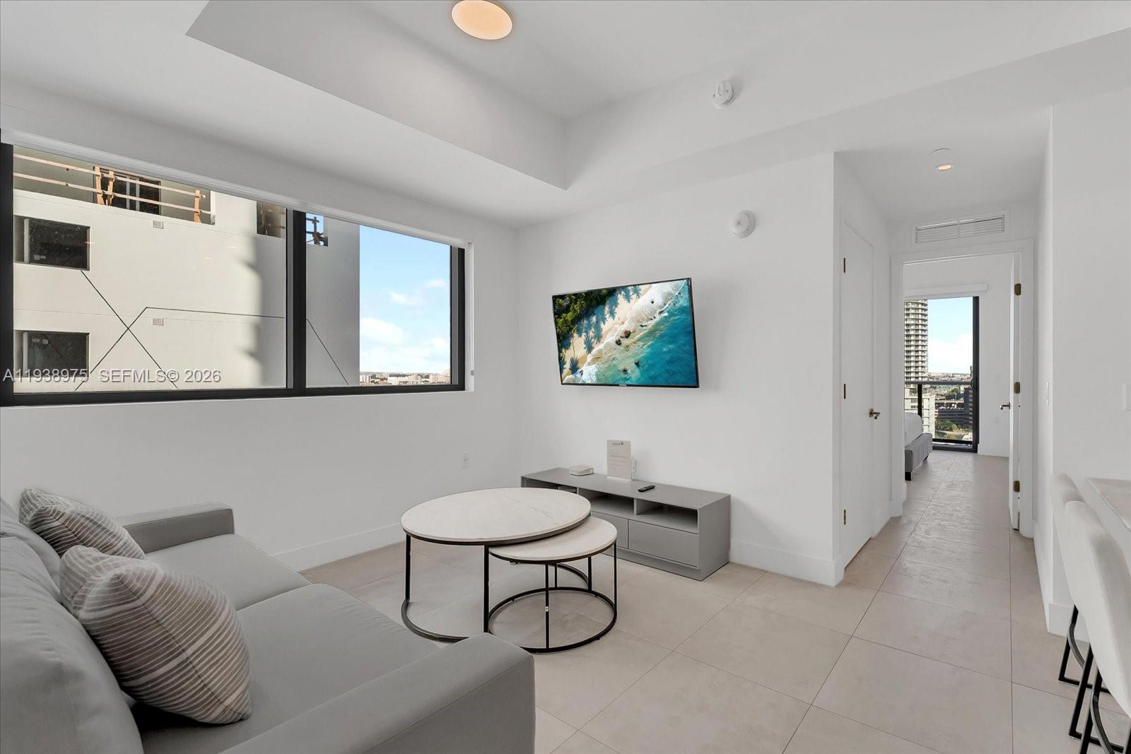 A modern living room features a gray sofa, nesting coffee tables, and a wall-mounted television — 239 SW 9th St # 1603, Miami FL 33130, MIAMI, FL