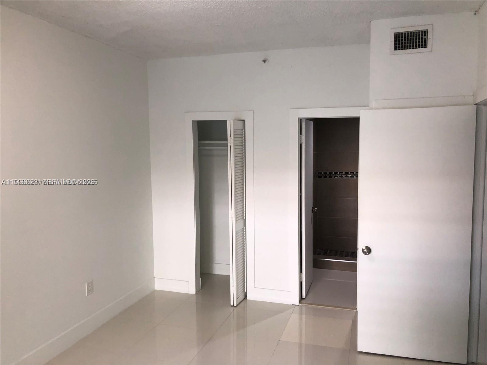 A room features white walls, tile flooring, a closet with louvered doors, and an adjacent bathroom — 2730 Collins Ave # 310, Miami Beach FL 33140, MIAMI BEACH, FL