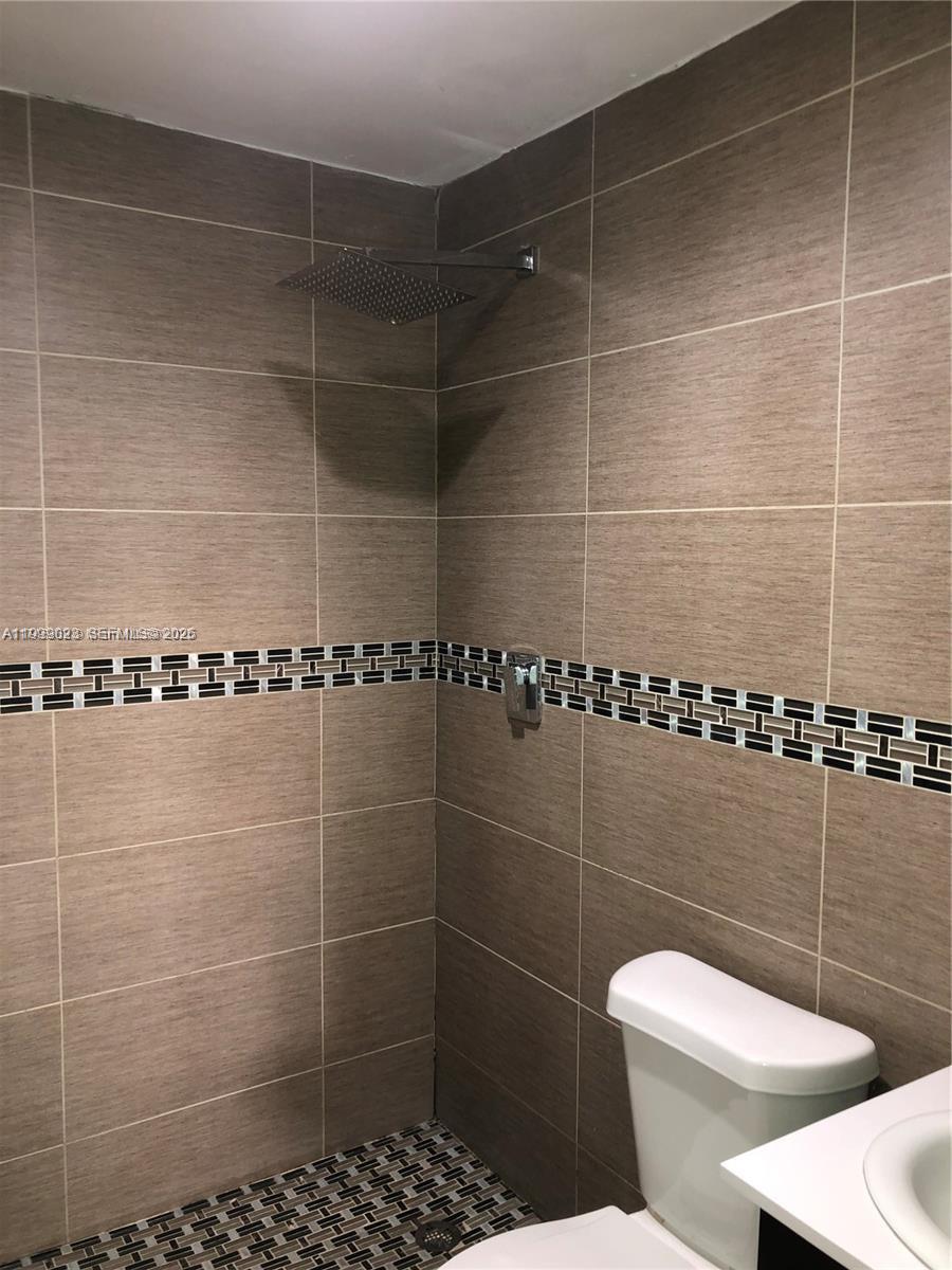 A bathroom features brown tiled walls, a decorative mosaic border, and a rainfall showerhead — 2730 Collins Ave # 310, Miami Beach FL 33140, MIAMI BEACH, FL
