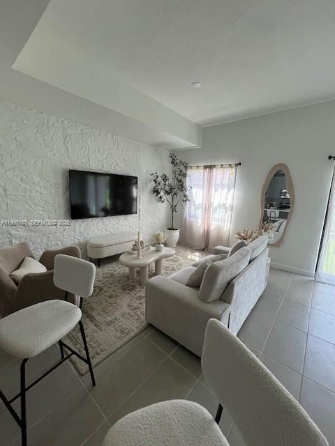 A living room features a textured white stone wall, a sofa, and a television — 2526 Pierce st # 10, Hollywood FL 33020, HOLLYWOOD, FL