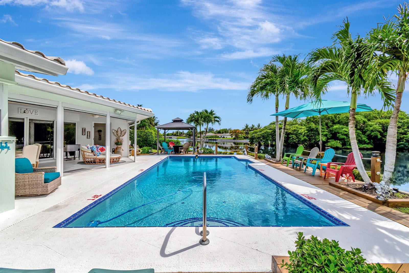 A swimming pool sits on a patio next to a house with palm trees — 302 Venice Drive, Boynton Beach FL 33426, BOYNTON BEACH, FL