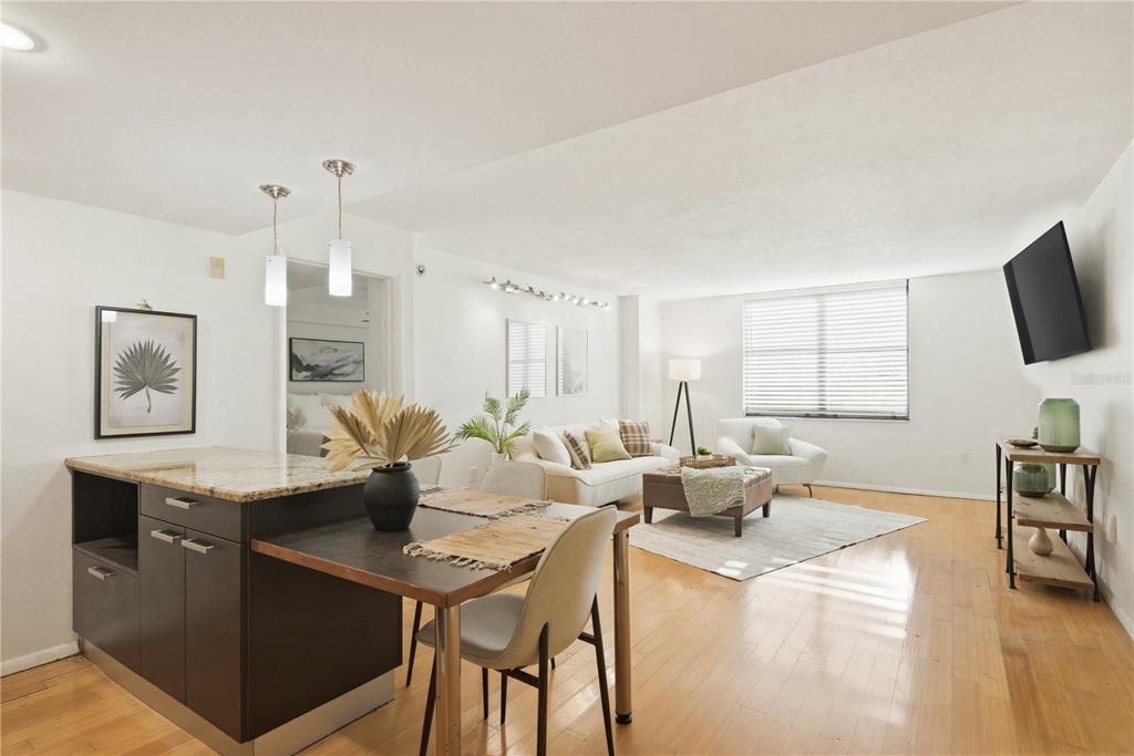 A bright, open-concept living and dining area features light wood floors and modern neutral furniture — 701 S MADISON AVENUE UNIT 420, CLEARWATER, FL