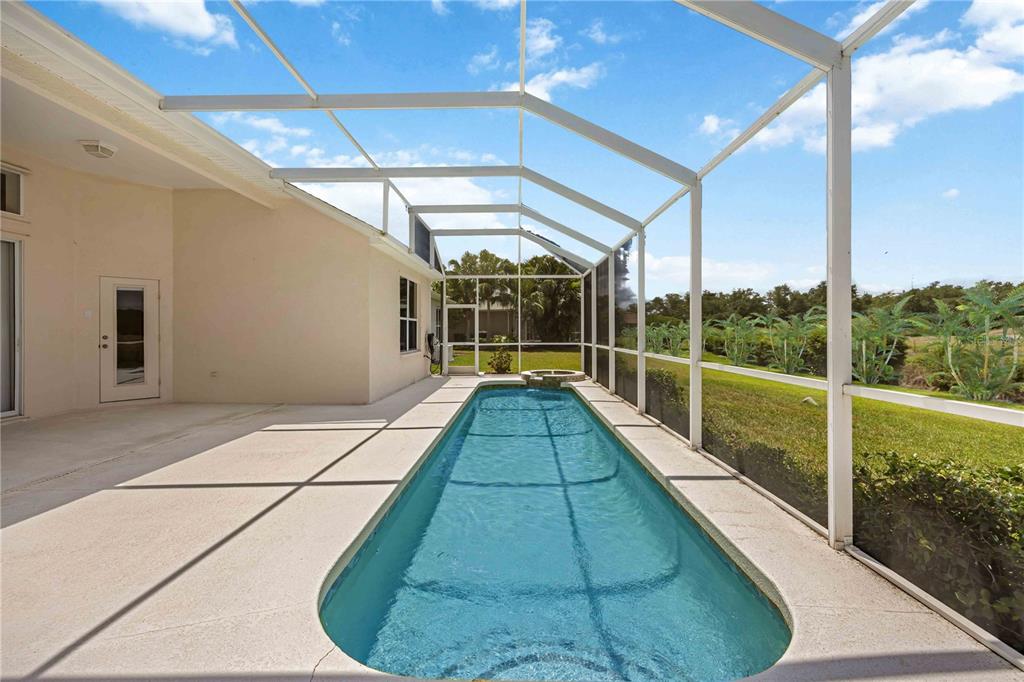 A rectangular swimming pool with a spa sits inside a screened-in patio enclosure — 7740 CASTLEISLAND DRIVE, SARASOTA, FL