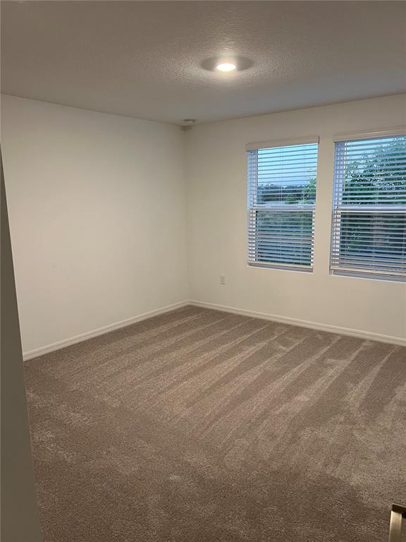 An empty bedroom features beige wall-to-wall carpeting, white walls, and two windows with blinds — 5080 REVOLUTIONARY WAY, ST CLOUD, FL
