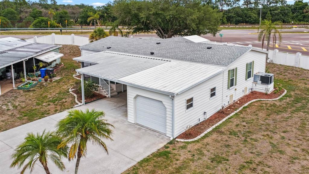 An aerial view shows a white house with a metal carport, garage, and palm trees — 194 S PORT ROYAL LANE, APOLLO BEACH, FL