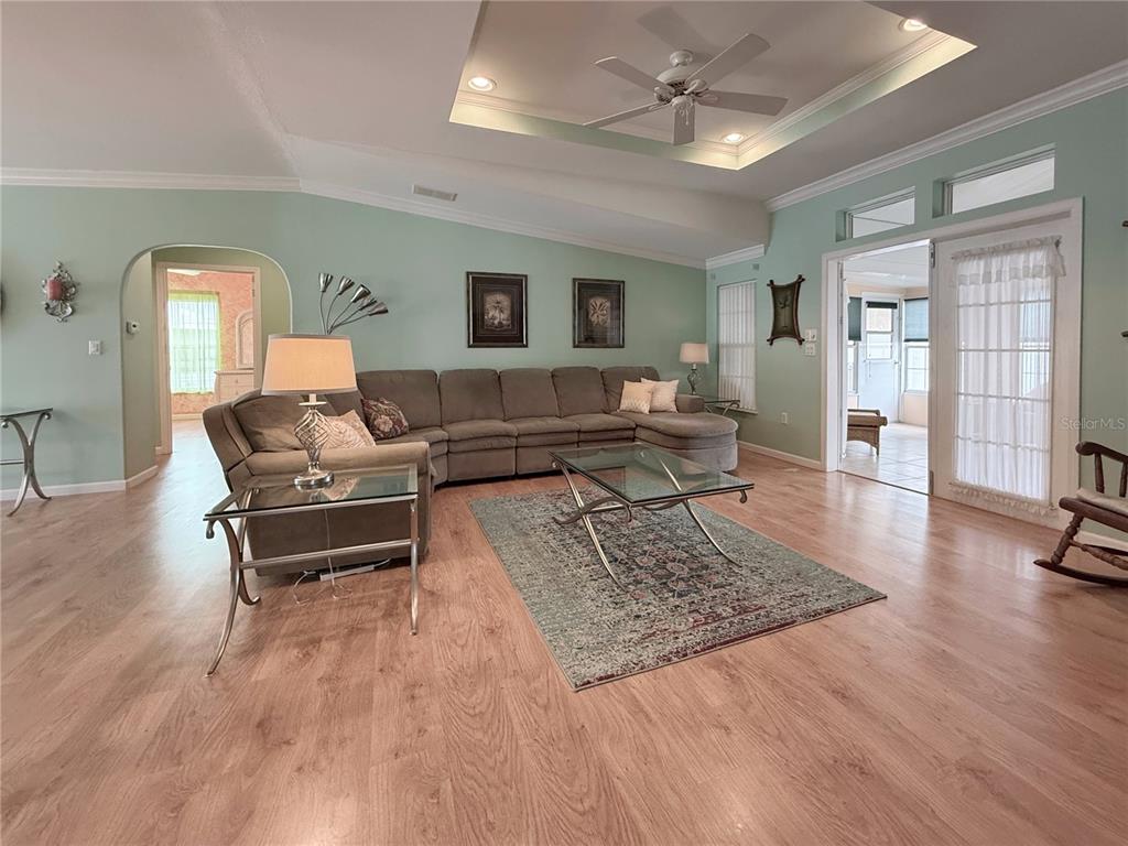 A living room features light green walls, wood-look flooring, a sectional sofa, and a ceiling fan — 194 S PORT ROYAL LANE, APOLLO BEACH, FL