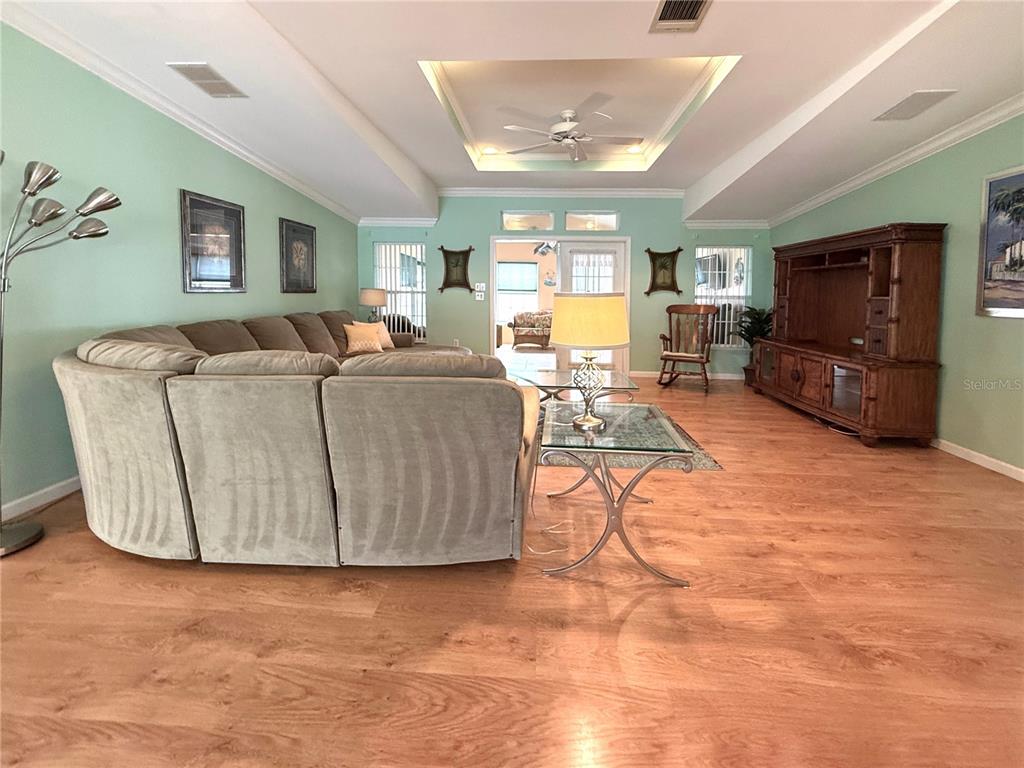 A living room features a large sectional sofa, wood flooring, and a tray ceiling — 194 S PORT ROYAL LANE, APOLLO BEACH, FL