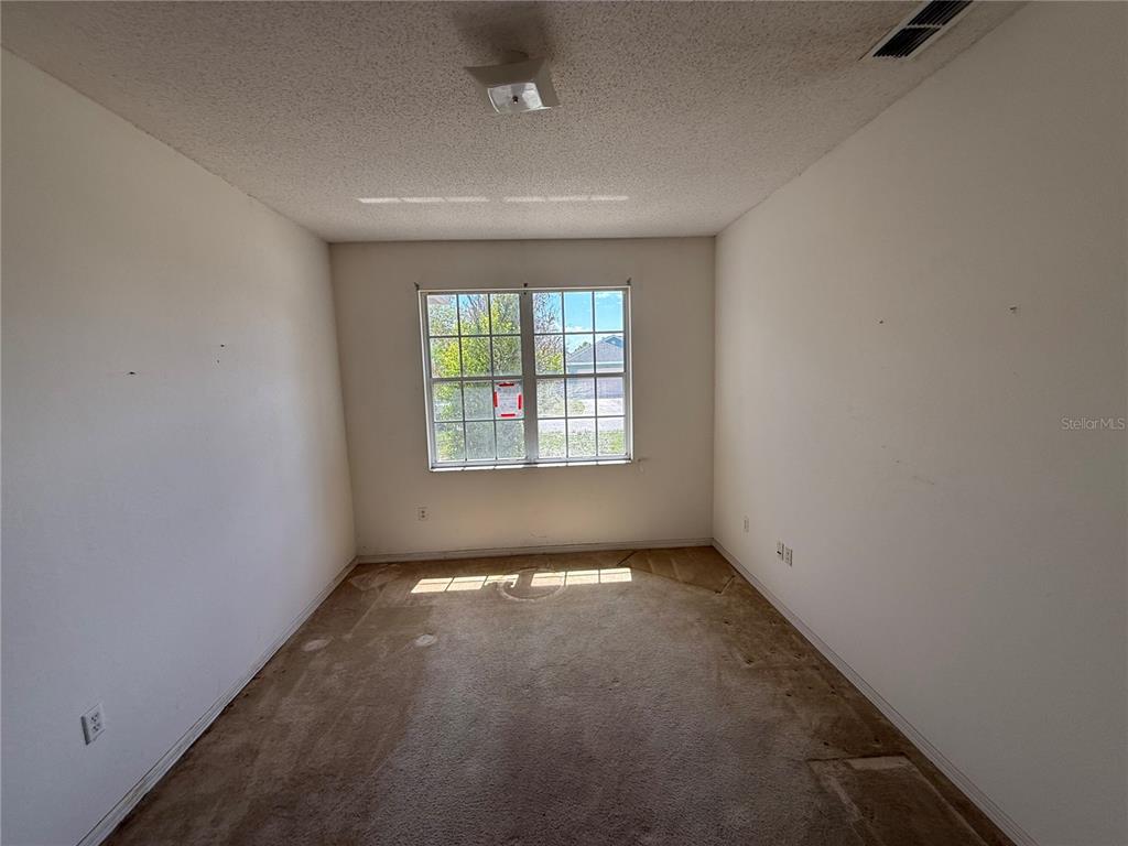 An empty bedroom features beige carpet, white walls, and a single window — 7422 GINGKO AVENUE, LAKELAND, FL
