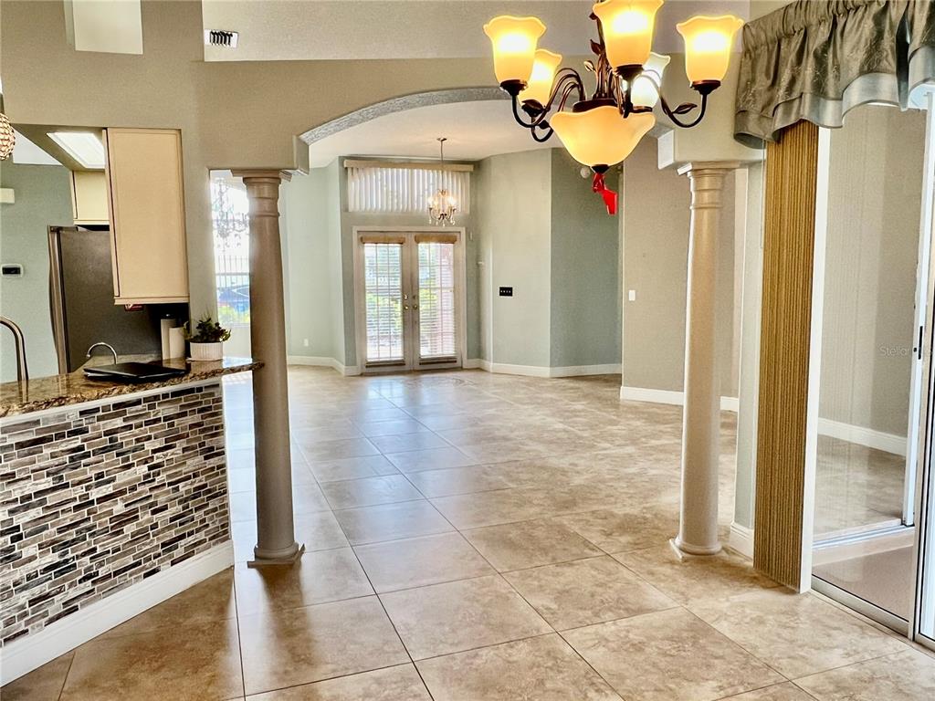 A view from a kitchen looking into a tiled living area with two decorative columns — 3715 72ND AVE E, SARASOTA, FL