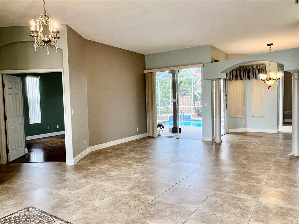 A tiled living area features a chandelier, arched entryways, and sliding doors opening to a pool — 3715 72ND AVE E, SARASOTA, FL