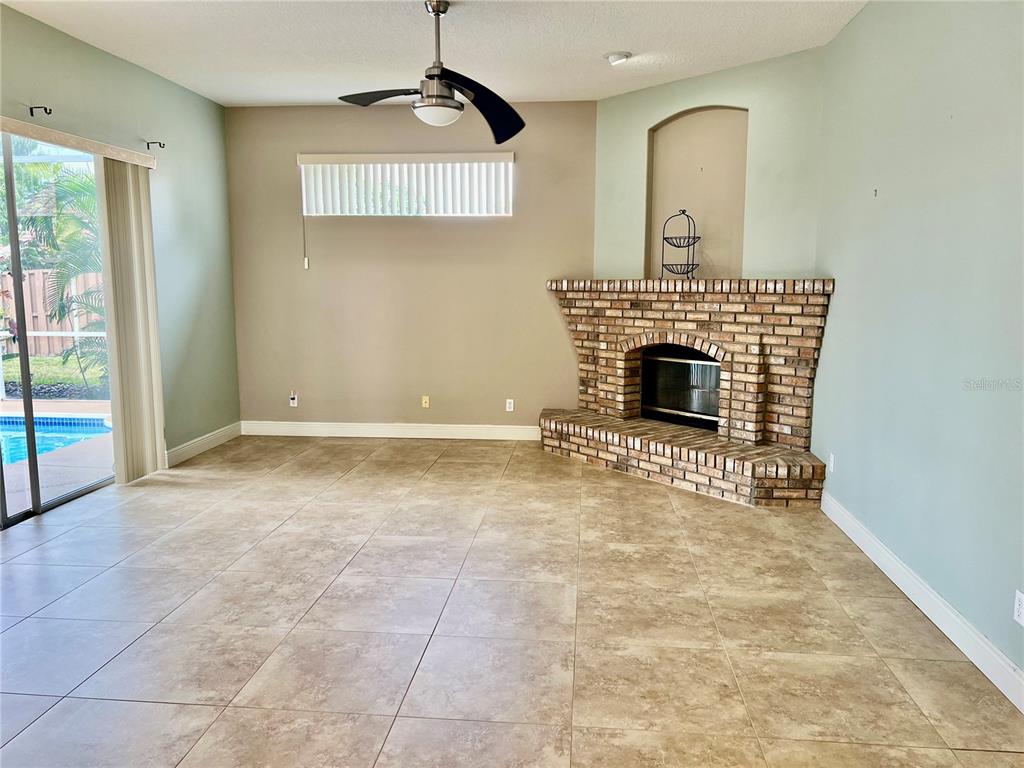 A living room features tile flooring, a corner brick fireplace, and sliding glass doors — 3715 72ND AVE E, SARASOTA, FL