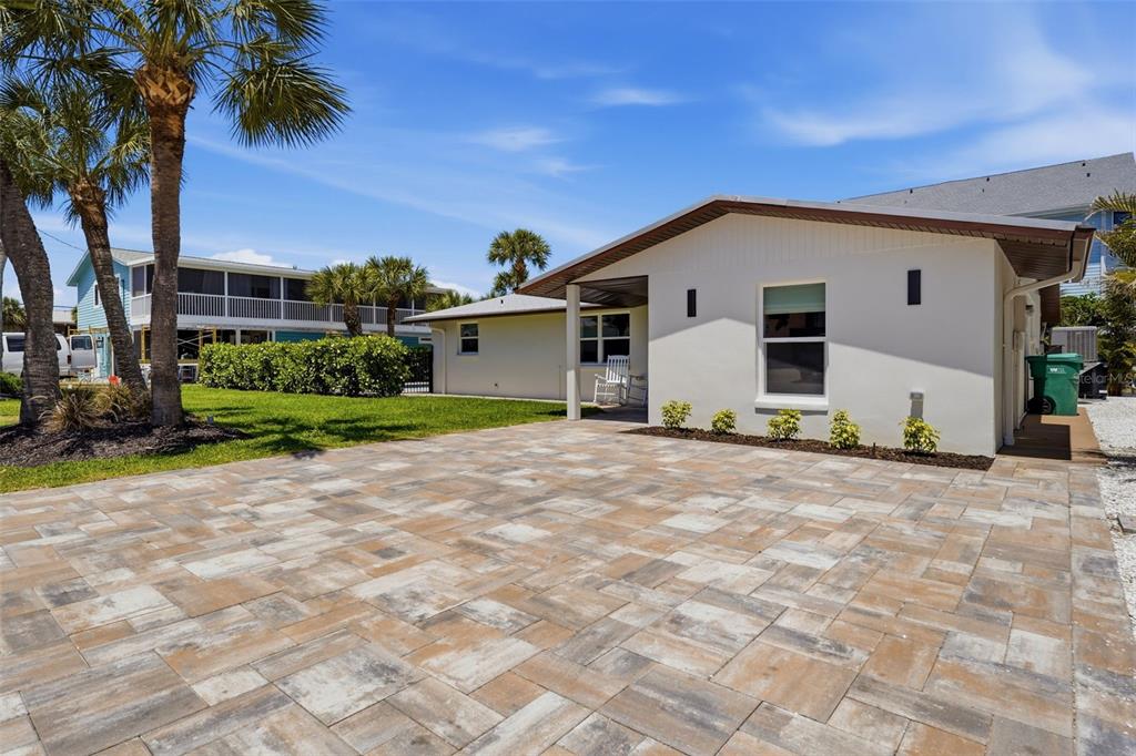 A paved driveway leads to the side entrance of a white house with palm trees — 120 STANFORD DRIVE, ENGLEWOOD, FL