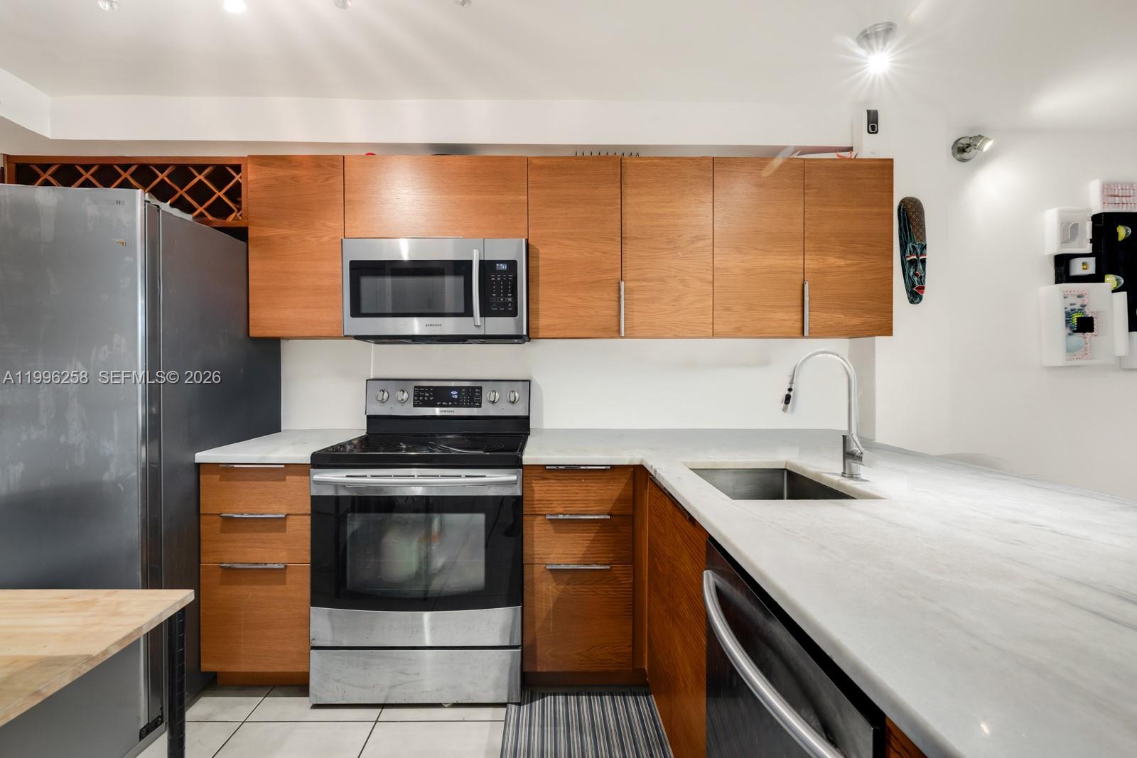 A kitchen features wood cabinets, stainless steel appliances, and white countertops — 680 NE 64th St # A300, Miami FL 33138, MIAMI, FL