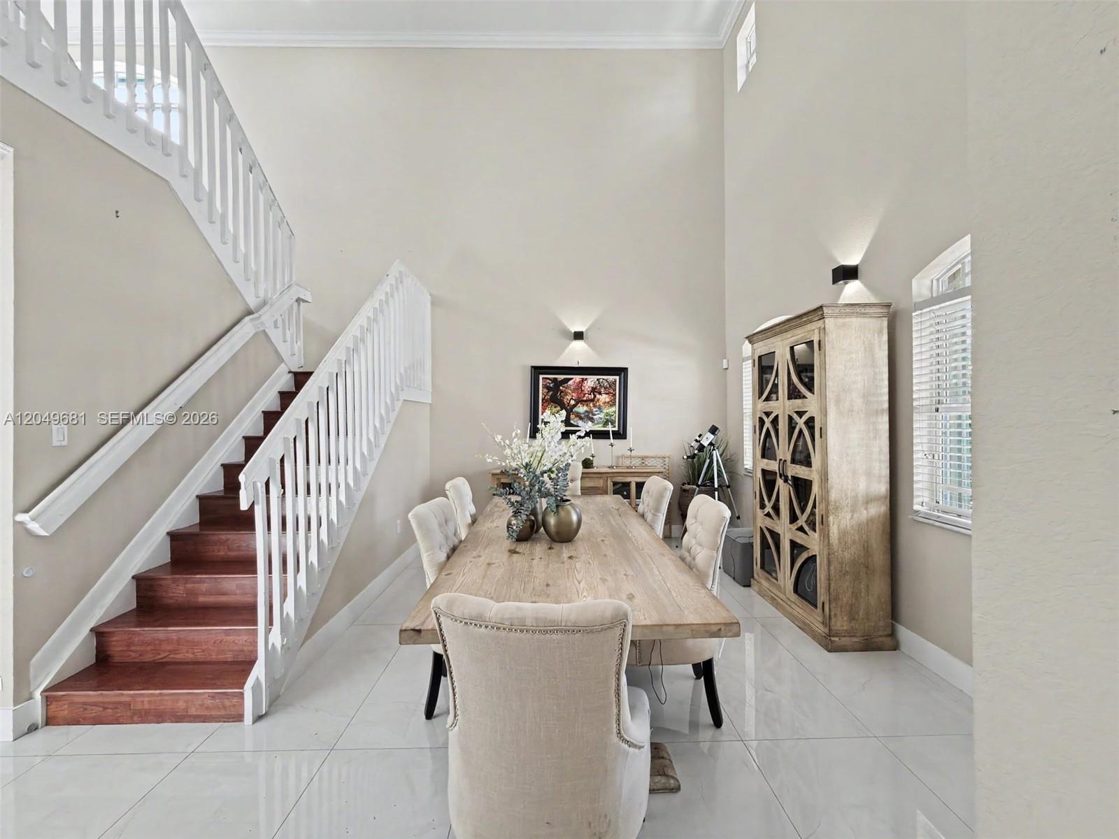 A dining room features a wooden table, upholstered chairs, a tall cabinet, and a staircase — 16519 SW 67th Ter, Miami FL 33193, MIAMI, FL
