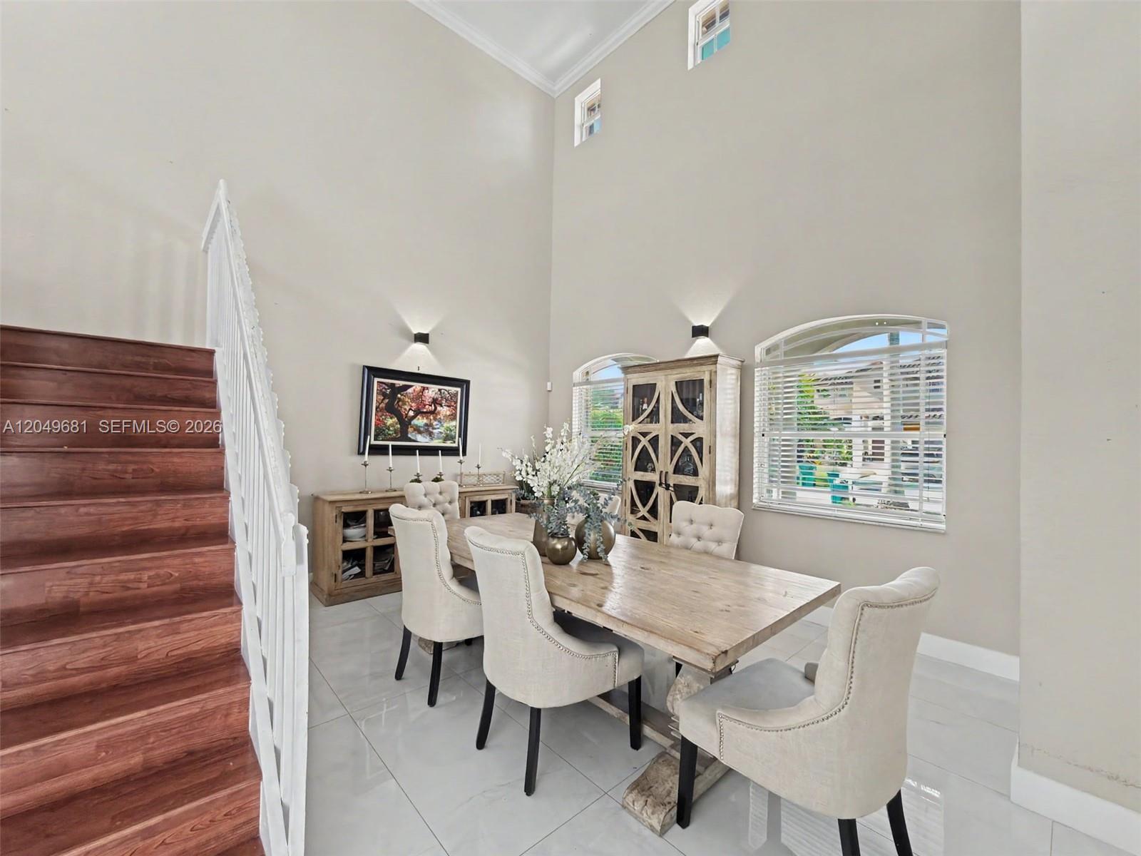 A dining room features a wooden table, upholstered chairs, a staircase, and high ceilings — 16519 SW 67th Ter, Miami FL 33193, MIAMI, FL