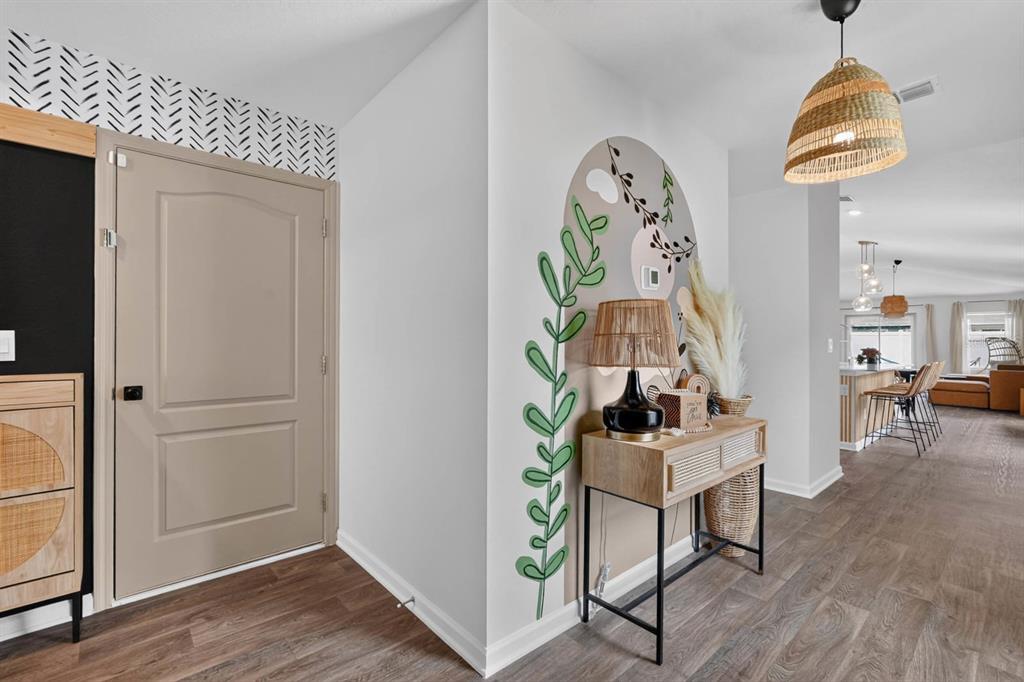 An entryway features a beige door, a console table, and a wall mural with greenery — 7 BILTMORE PLACE, PALM COAST, FL
