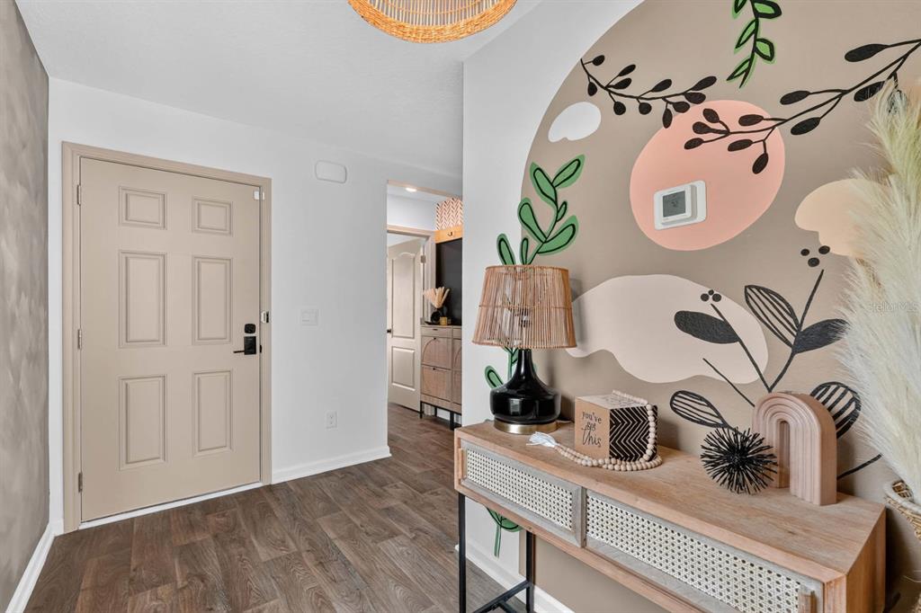 An entryway features a tan door, wood-look flooring, and a wall with a floral mural — 7 BILTMORE PLACE, PALM COAST, FL