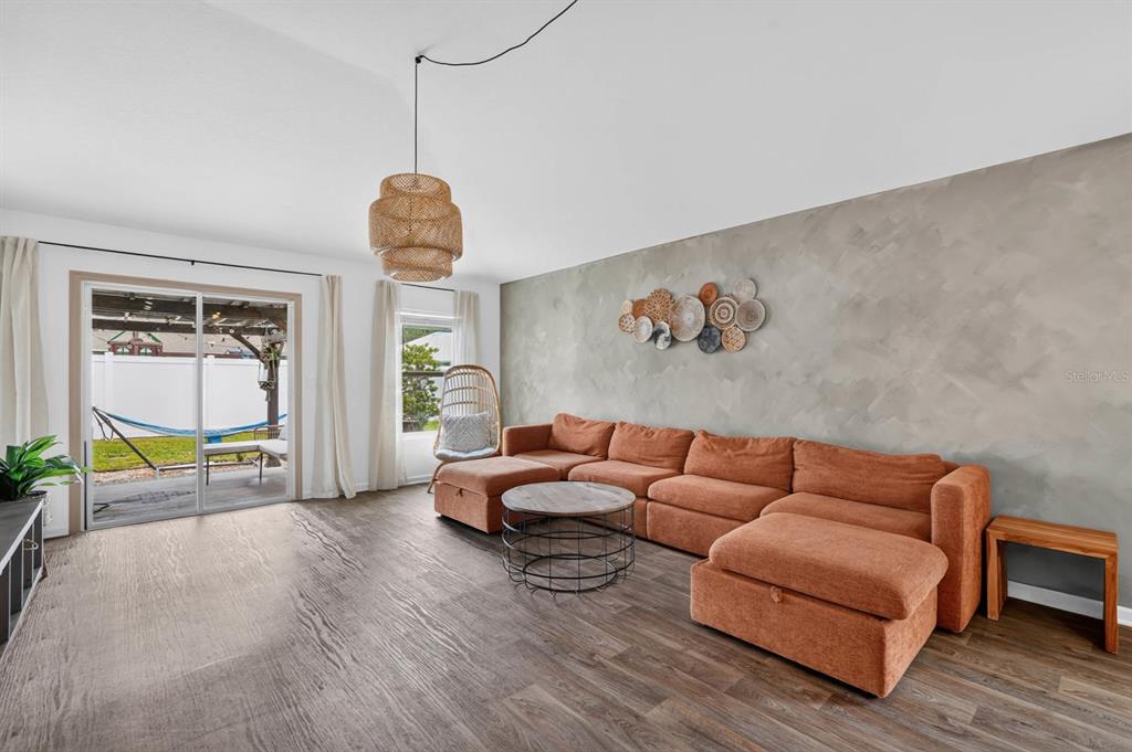 A living room features a large orange sectional, a textured accent wall, and a woven pendant — 7 BILTMORE PLACE, PALM COAST, FL