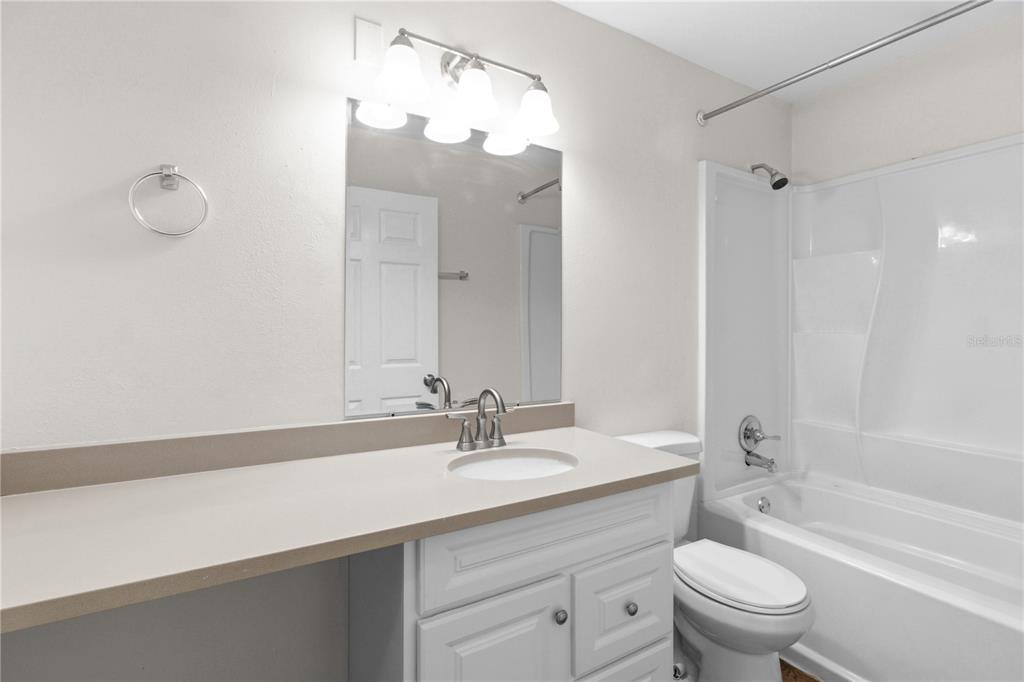 A bathroom features a white vanity with a beige countertop, a mirror, and a tub-shower — 929 SANDYWOOD DRIVE, BRANDON, FL