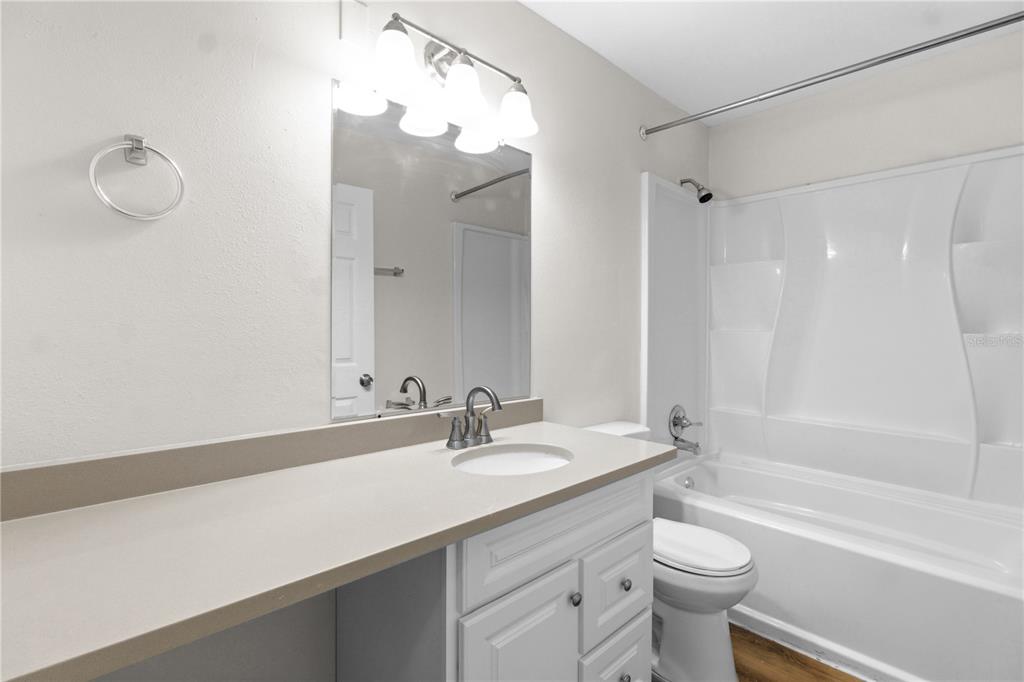 A bathroom features a white vanity with a sink, a mirror, and a tub-shower combo — 929 SANDYWOOD DRIVE, BRANDON, FL
