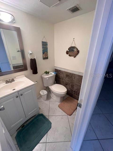 A bathroom features a white vanity, a toilet, tiled flooring, and a wall-mounted fish decoration — 1614 STICKNEY POINT ROAD UNIT 102, SARASOTA, FL